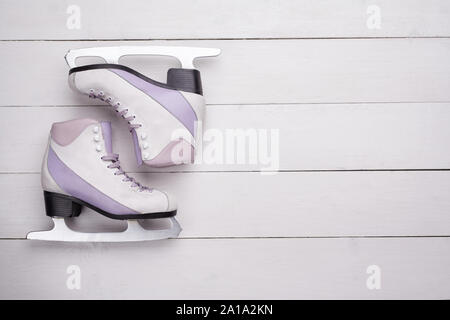 Close-up photo of professional ice skates lying on a white wooden background. Stock Photo