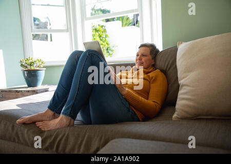 Mature woman alone at home using tablet Stock Photo