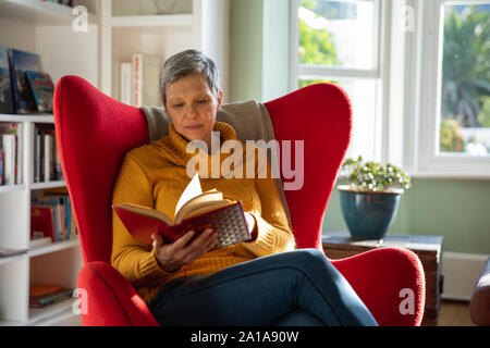 Mature woman alone at home reading book Stock Photo