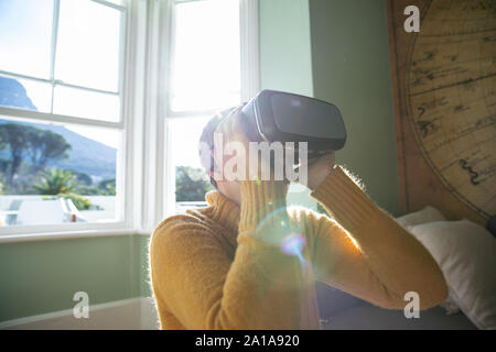 Mature woman alone at home in VR headset Stock Photo