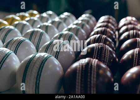 Red, white and yellow cricket balls in rows Stock Photo