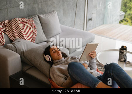 Young brunette woman watching tablet with headphones on Stock Photo
