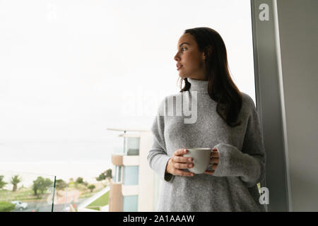Young woman on balcony holding a cup of coffee Stock Photo