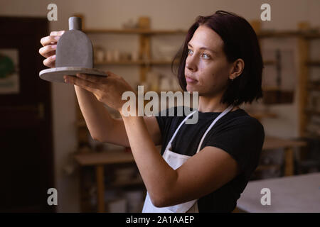 Female potter in a pottery studio holding a flask Stock Photo