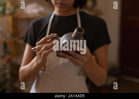 Female potter in a pottery studio holding a flask Stock Photo