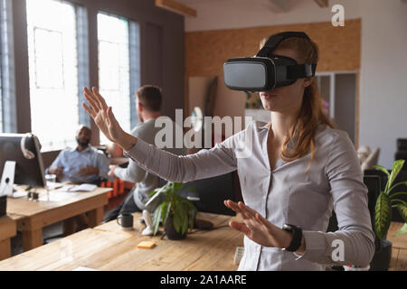 Young creative professional woman using VR headset in a sunlit office Stock Photo