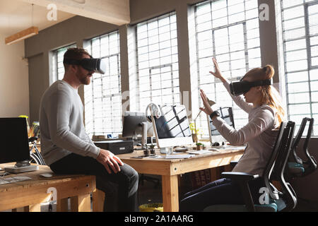 Young creative professionals using VR headsets in a sunlit office Stock Photo