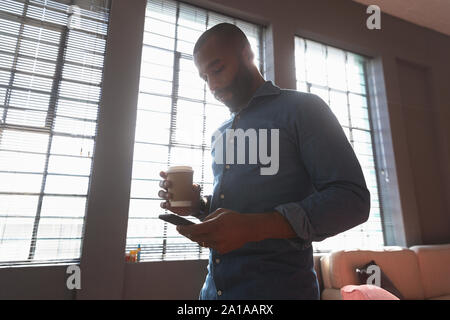 Young creative professional using smartphone in a sunlit office Stock Photo