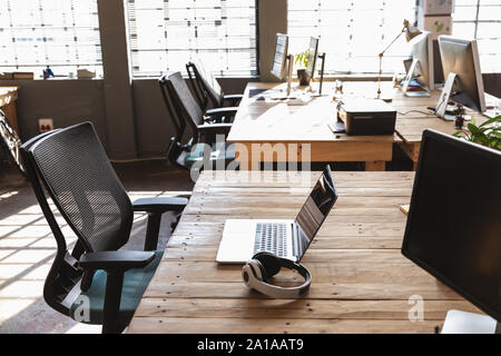 Desks and computers in a sunlit creative office Stock Photo
