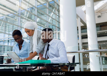 Male and females executives discussing over digital tablet at desk Stock Photo