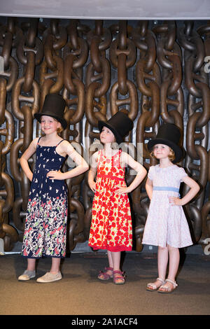 Three sisters children / kids / child / kid wearing top hat and pose in front of large chains to emulate the famous photograph of Isambard Kingdom Brunel taken by Robert Howlett. Taken at the Being Brunel exhibition accompanying the SS Great Britain ship, Dockyard, Bristol England UK (109) Stock Photo