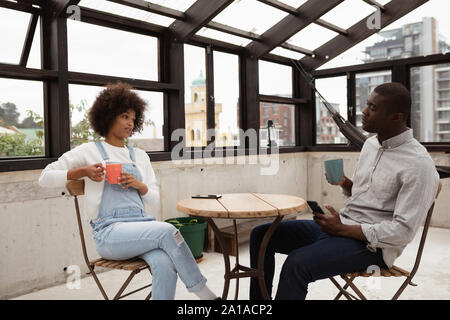 Couple drinking coffee and talking at a table Stock Photo