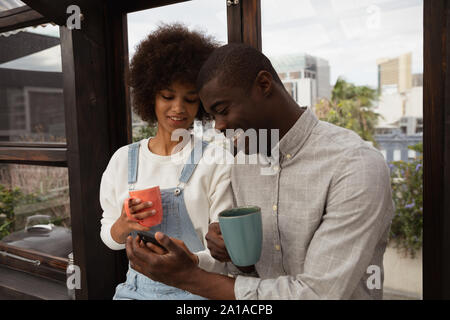 Couple drinking coffee and using smartphone Stock Photo