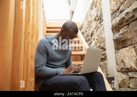 Young man using laptop on staircase Stock Photo