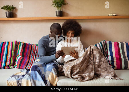 Couple using a tablet on a sofa Stock Photo