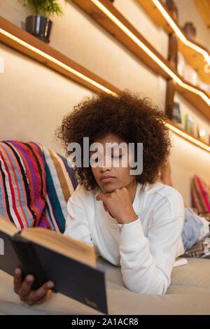 Woman reading lying on a sofa Stock Photo