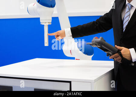 The engineer demonstrates the work of the robot-collaborator Stock Photo