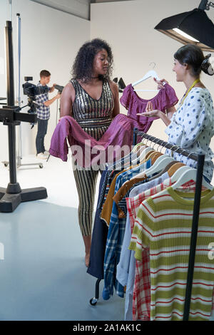 Stylist Choosing Clothes For Fashion To Wear On Photo Shoot In Studio Stock Photo