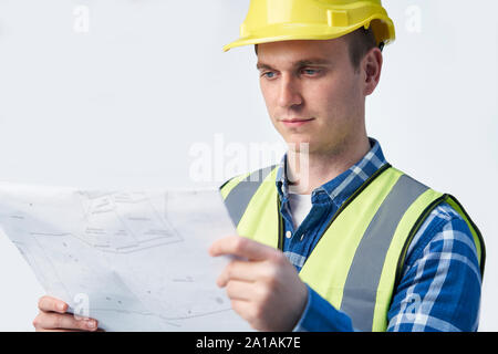 Studio Shot Of Builder Architect Looking At Plans Against White Background Stock Photo