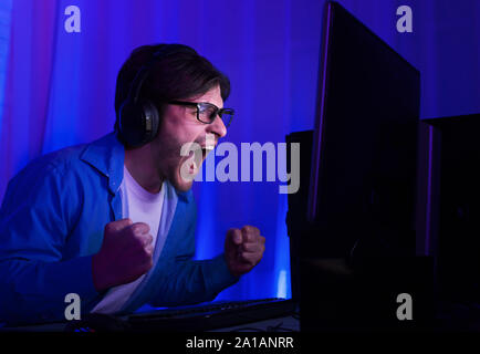 Gaming concept. Happy man in glasses celebrating victory in game Stock Photo