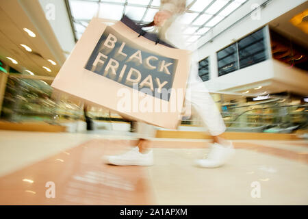 Close-up of young woman holding shopping bags and doing purchases during black friday in the mall Stock Photo