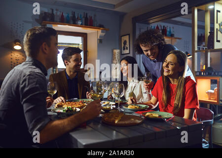 Young people meeting friends for dinner in a restaurant Stock Photo