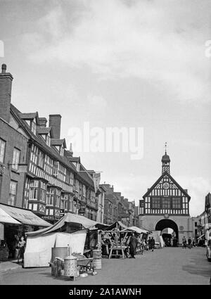 A mid Twentieth Century black and white photograph showing the High Street in Bridgnorth, Shropshire, England. Image shows the 17th Century Town Hall building in the background, and many shops including Boots The Chemist, and Tanners Wine Shop, Stock Photo