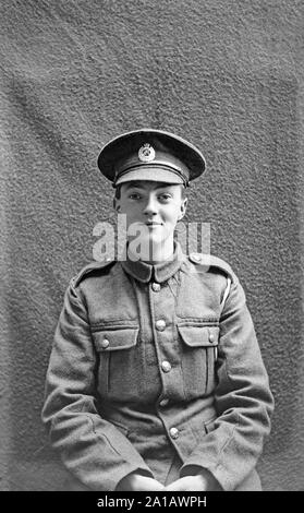 A vintage British Studio black and white portrait photograph of a very young man in a soldiers uniform, taken between 1914 and 1918, during the years of the First World war. The boy is smiling and looks happy. Stock Photo