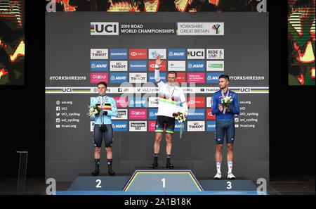 Australia's Rohan Dennis (centre) celebrates on the podium after winning gold alongside silver medalist Belgium's Remco Evenepoel (left) and bronze medalist Italy's Filippo Ganna during the Men's Elite Individual Time Trials from Northallerton to Harrogate. Stock Photo