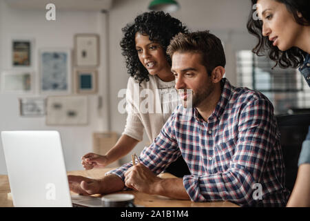 Three diverse designers using a laptop together at work Stock Photo