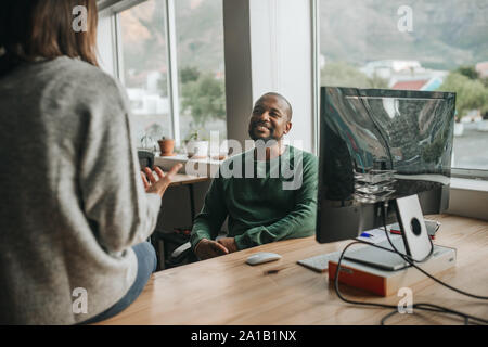 Smiling African American designer talking with a colleague at work Stock Photo