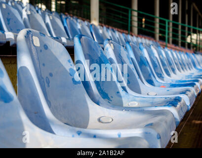 empty rows of wet blue plastic seats in the stadium Stock Photo