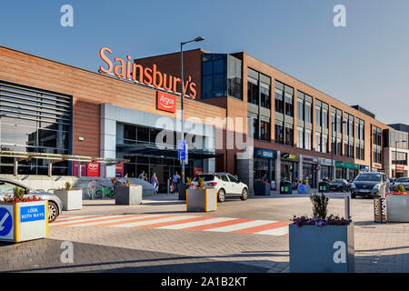 Longbridge town centre dominated by Sainsbury's superstore. In front of the store a road sign advises of a shared space for traffic and pedestrians. Stock Photo