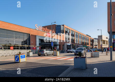 Longbridge town centre dominated by Sainsbury's superstore. In front of the store a road sign advises of a shared space for traffic and pedestrians. Stock Photo