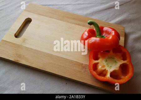 Red capsicum pepper cut in half on wood chopping board Stock Photo