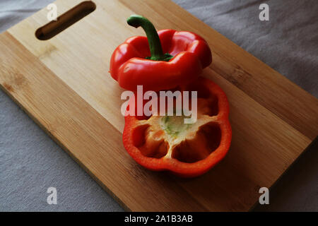 Red capsicum pepper cut in half on wood chopping board Stock Photo