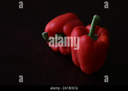 Red capsicum peppers against a black background Stock Photo