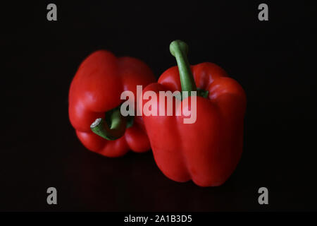 Red capsicum peppers against a black background Stock Photo