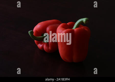 Red capsicum peppers against a black background Stock Photo