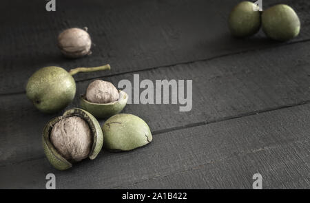 Walnuts in a green shell on a wooden table Stock Photo
