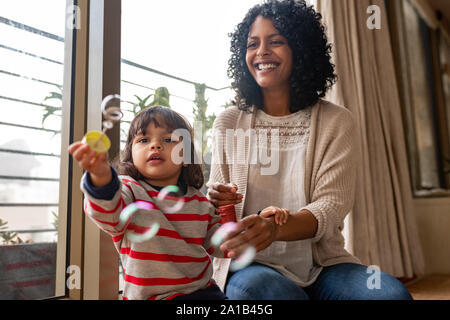 Little girl and her mother playing with a bubble wand Stock Photo