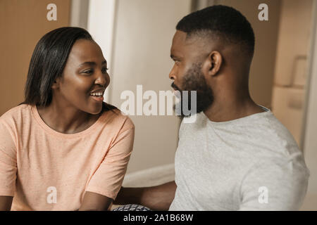 Smiling young African American couple talking together on their bed Stock Photo