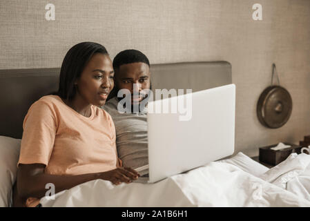 Young African American couple using a laptop together in bed Stock Photo