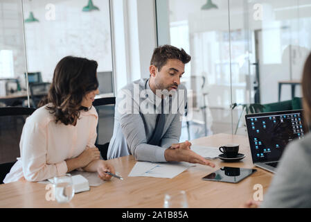 Two businesspeople discussing work with office colleagues during a meeting Stock Photo