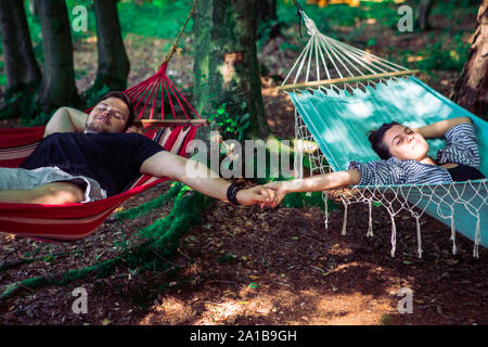 couple laying in hammocks in forest Stock Photo