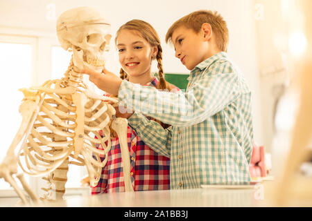 Positive delighted kids examining skeleton in classroom Stock Photo