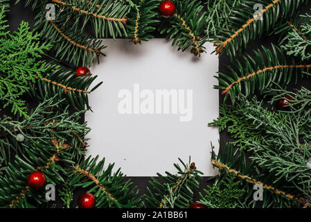 Creative layout made of Christmas tree branches with paper card note. Flat lay. Nature New Year concept. Stock Photo