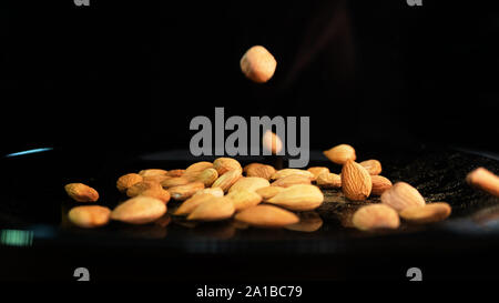 Almond and apricot grains, on the varnished plate falling seeds. The use of almonds in the culinary industry and advertising trade Stock Photo