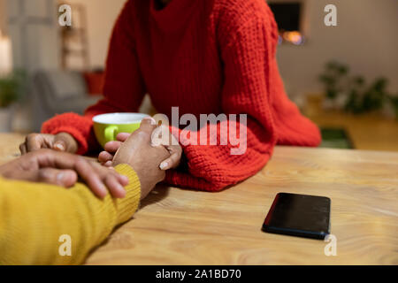 Millennial couple sitting holding hands at home Stock Photo