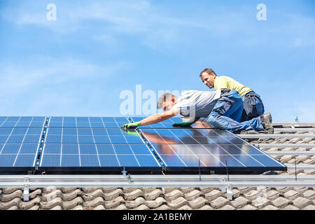 Installing solar photovoltaic panel system. Solar panel technician installing solar panels on roof. Alternative energy ecological concept. Stock Photo